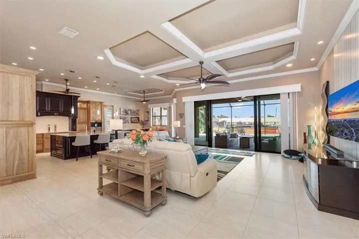 Living room with recessed lighting, coffered ceiling, crown molding, a ceiling fan, and light tile patterned floors