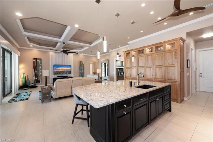 Kitchen with a ceiling fan, decorative light fixtures, arched walkways, a large island with sink, and coffered ceiling