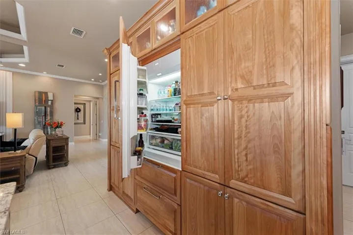 Kitchen with recessed lighting, glass insert cabinets, open floor plan, light tile patterned floors, and crown molding