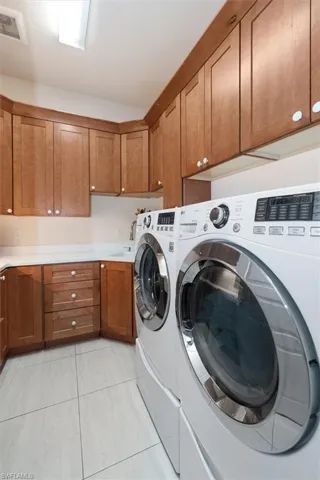 Laundry room with cabinet space, washing machine and clothes dryer, and light tile patterned floors