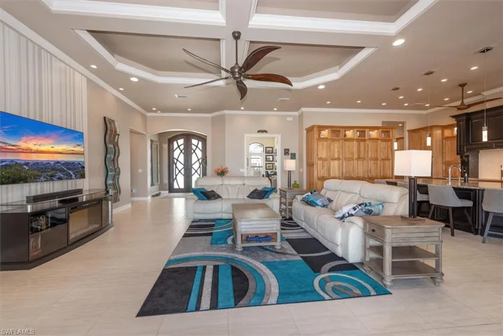 Living room with ceiling fan, recessed lighting, arched walkways, a raised ceiling, and crown molding