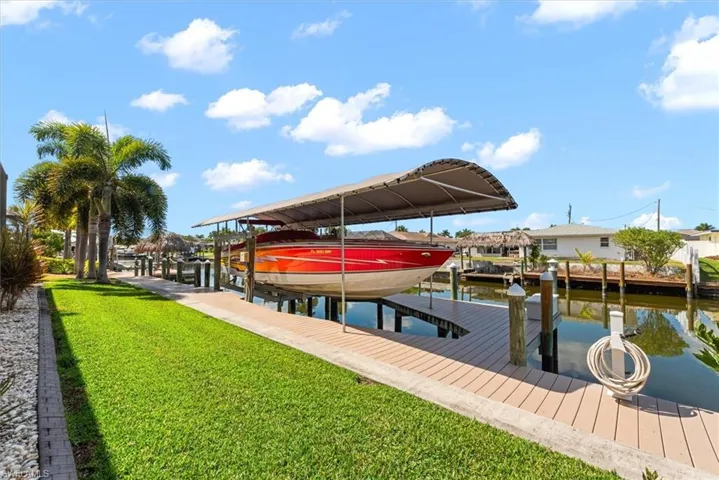 Dock featuring boat lift, a water view, and a lawn