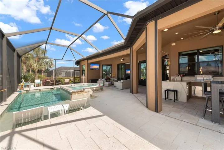 Relaxing pool / spa with a patio area, a sunroom, a lanai, and an outdoor lounge area with bar