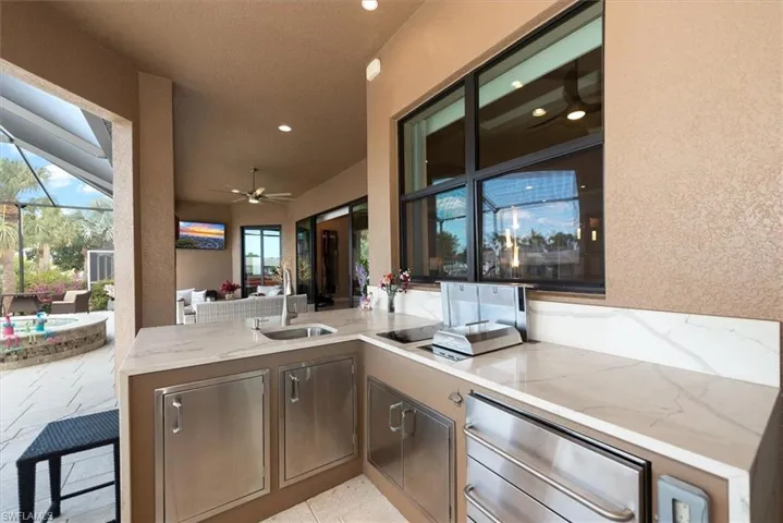View of patio / terrace with ceiling fan, an outdoor kitchen, glass enclosure, an outdoor lounge area with bar, and a sunroom