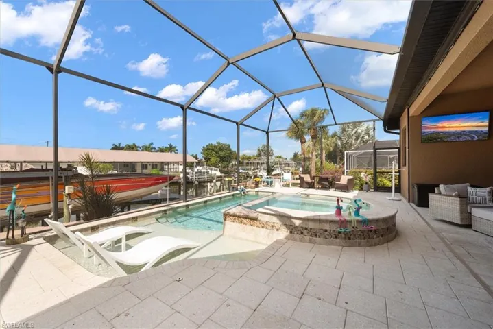 Relaxing pool / spa featuring a sunroom, a lanai, a patio area, a boat dock, and an outdoor living space