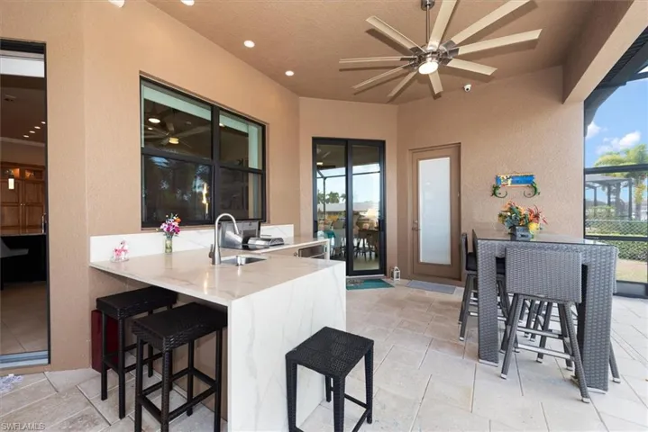 View of patio featuring an outdoor bar and dining area, a ceiling fan, and exterior kitchen