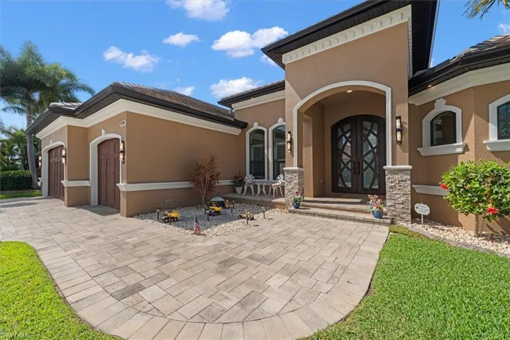 View of exterior entry with an attached garage, stucco siding, driveway, and a tiled roof