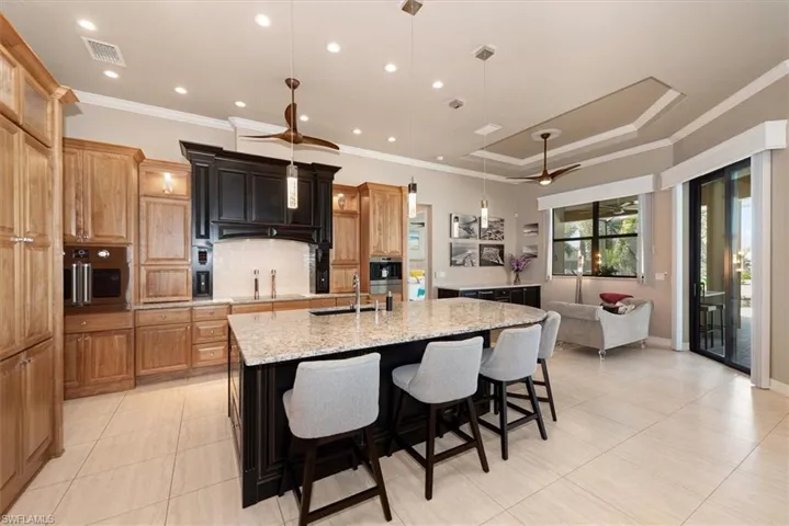 Kitchen with a kitchen breakfast bar, backsplash, a large island, light stone countertops, and pendant lighting
