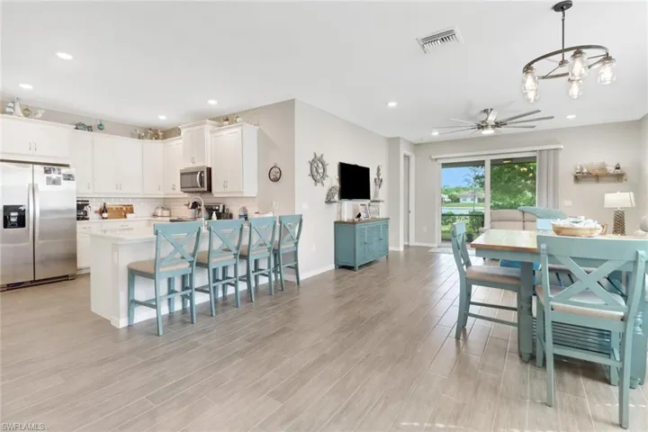 Kitchen featuring white cabinets, tile flooring, tasteful backsplash, decorative light fixtures, and stainless steel appliances