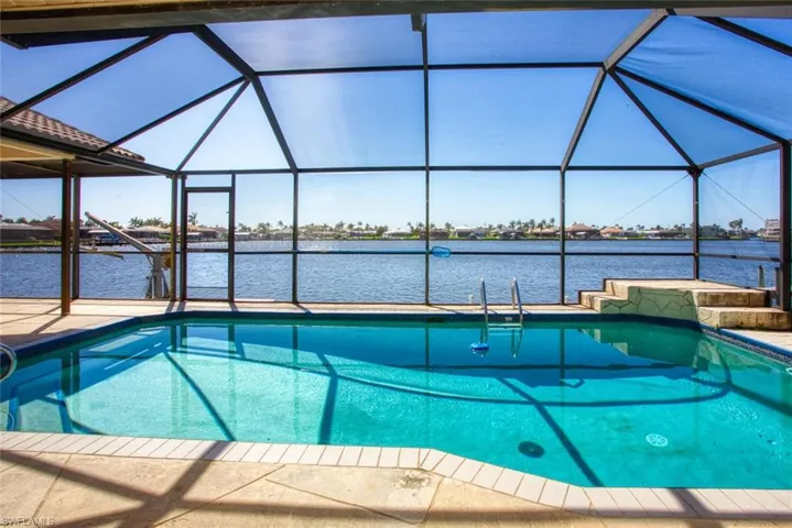 Outdoor pool with a patio area, glass enclosure, and a water view
