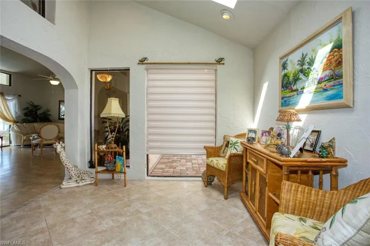 Sitting room with lofted ceiling with skylight, arched walkways, light tile patterned flooring, and a textured wall