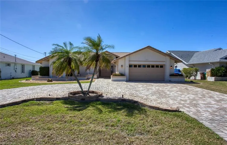 View of front of home featuring a garage, a front lawn, and decorative driveway