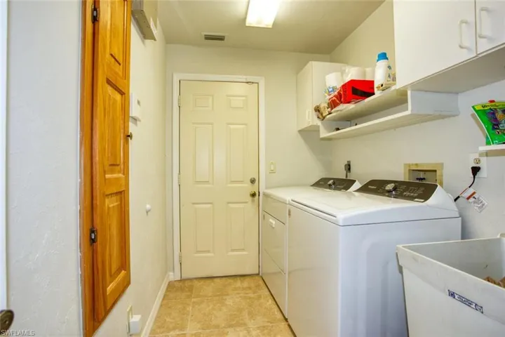 Laundry area featuring light tile patterned floors, cabinet space, visible vents, a sink, and washer and dryer