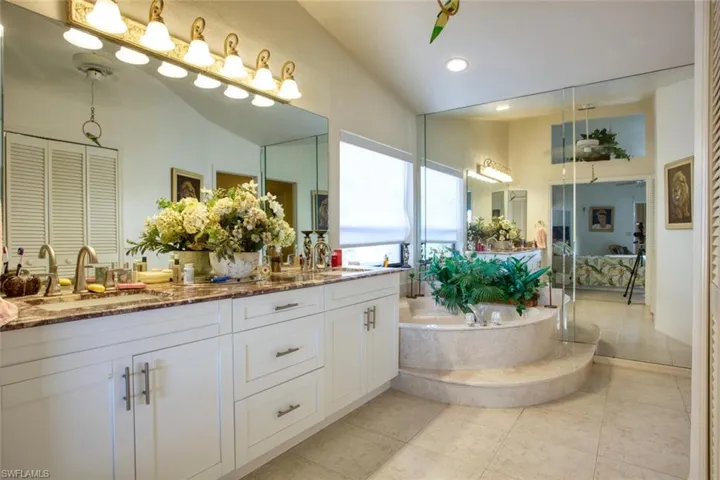 Full bath featuring double vanity, tile patterned flooring, a sink, and a bath