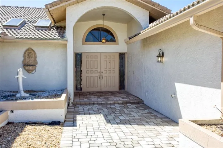 Entrance to property with a tile roof and stucco siding