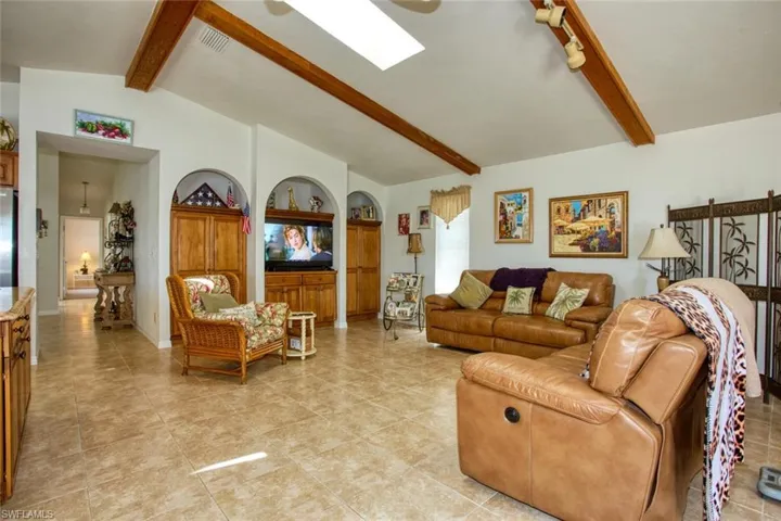 Living area featuring lofted ceiling with beams, built in shelves, and visible vents