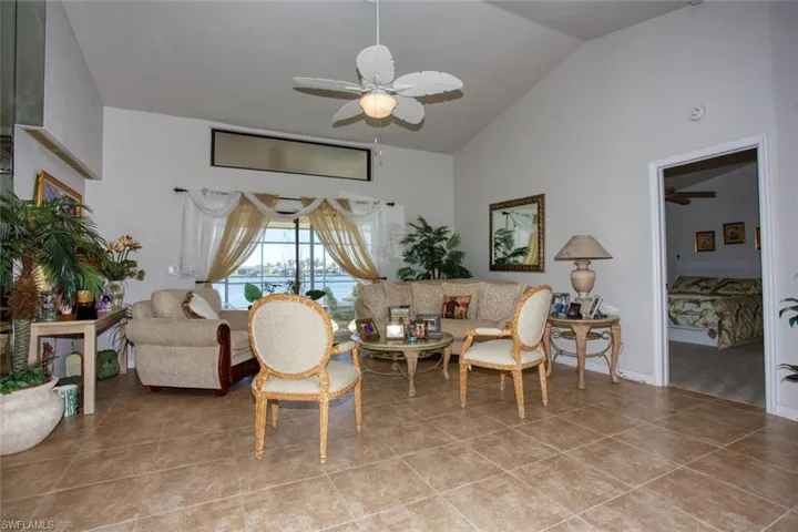 Living area with a ceiling fan, lofted ceiling, and tile patterned floors