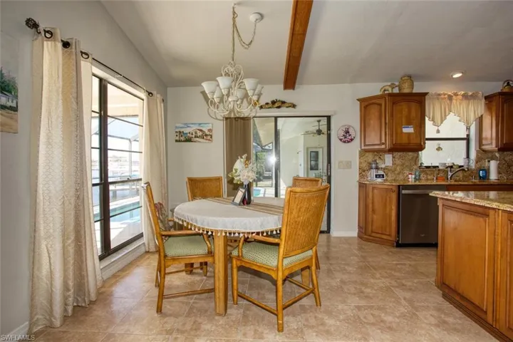 Dining space featuring vaulted ceiling with beams, an inviting chandelier, and baseboards