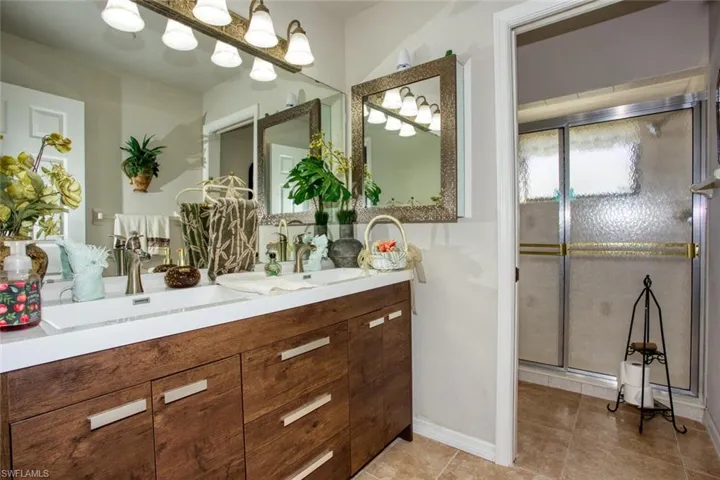 Full bath featuring double vanity, tile patterned flooring, a sink, and a shower with shower door