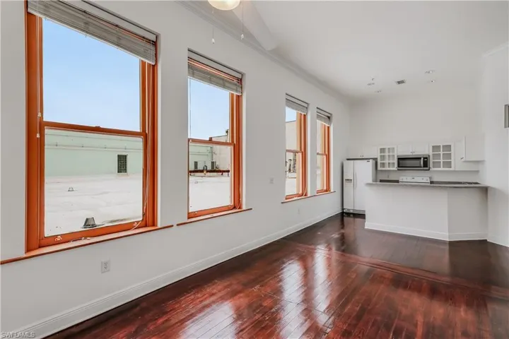 Unfurnished living room featuring ornamental molding and dark hardwood / wood-style floors