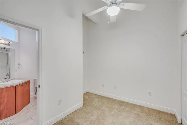 Carpeted bedroom with sink and ceiling fan