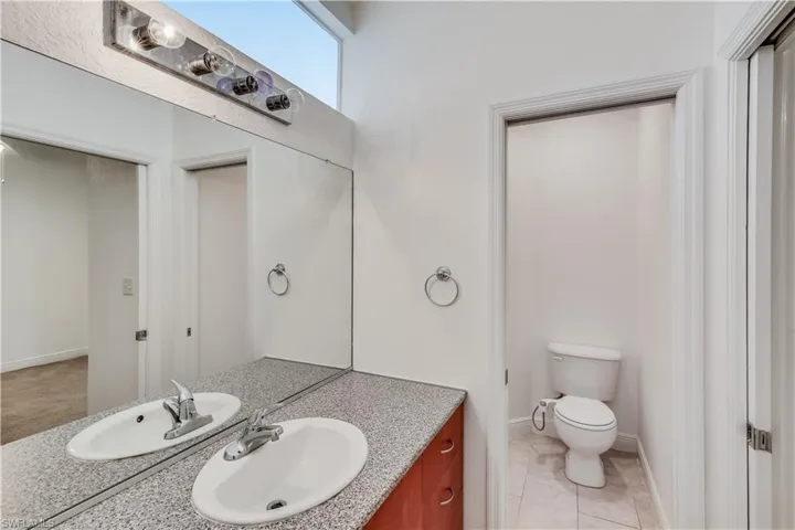 Bathroom featuring tile flooring, toilet, and large vanity