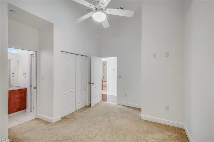 Unfurnished bedroom with a towering ceiling, a closet, ceiling fan, and light colored carpet