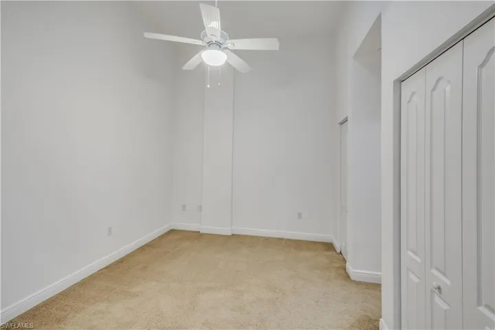 Unfurnished bedroom with ceiling fan and light colored carpet