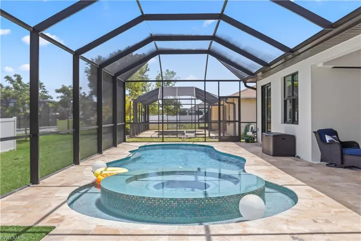 Swimming pool with a hot tub, a patio, glass enclosure, and a yard