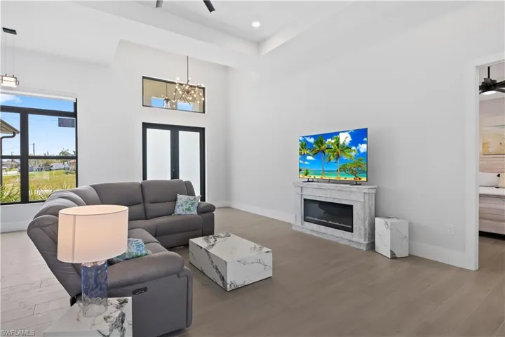 Living room featuring wood finished floors, a high end fireplace, a chandelier, recessed lighting, and a tray ceiling