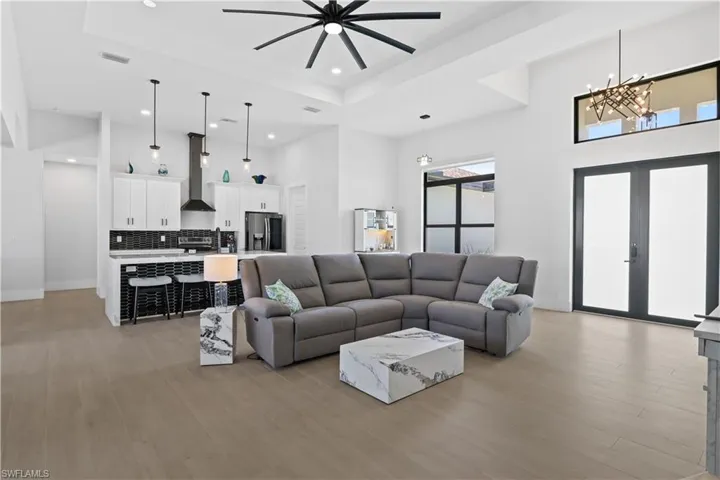 Living area featuring recessed lighting, a tray ceiling, a ceiling fan, a high ceiling, and a chandelier