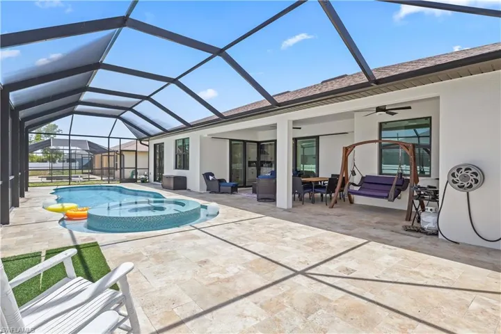 Outdoor pool with ceiling fan, a patio area, outdoor lounge area, and glass enclosure