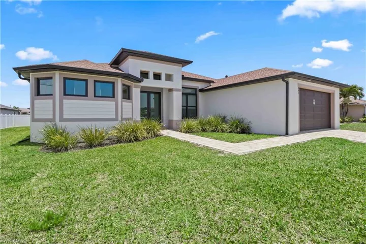 Prairie-style house with stucco siding, an attached garage, french doors, and driveway
