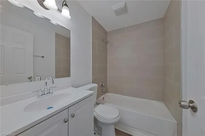 Full bathroom with tiled shower / bath combo, toilet, and vanity