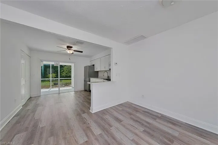 Unfurnished living room with light hardwood / wood-style flooring, sink, and ceiling fan