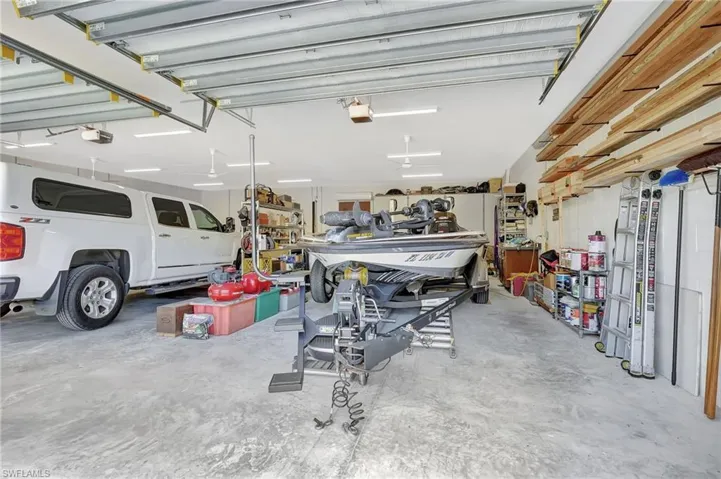 Spacious garage featuring a concrete floor, overhead garage door rails, multiple ceiling fans, recessed lighting, and built-in shelving