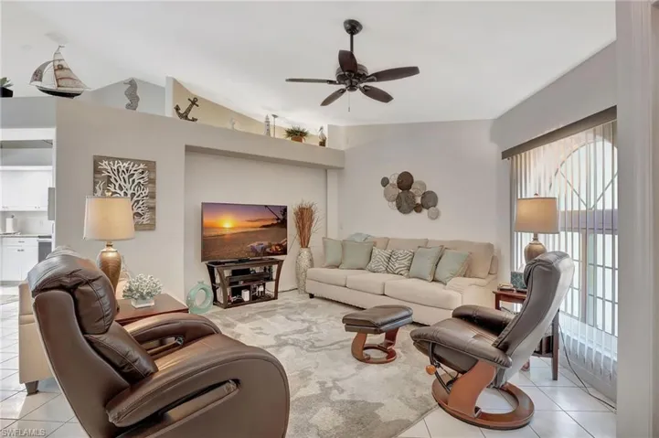 Spacious living area featuring high vaulted ceilings, a ceiling fan, and tile flooring