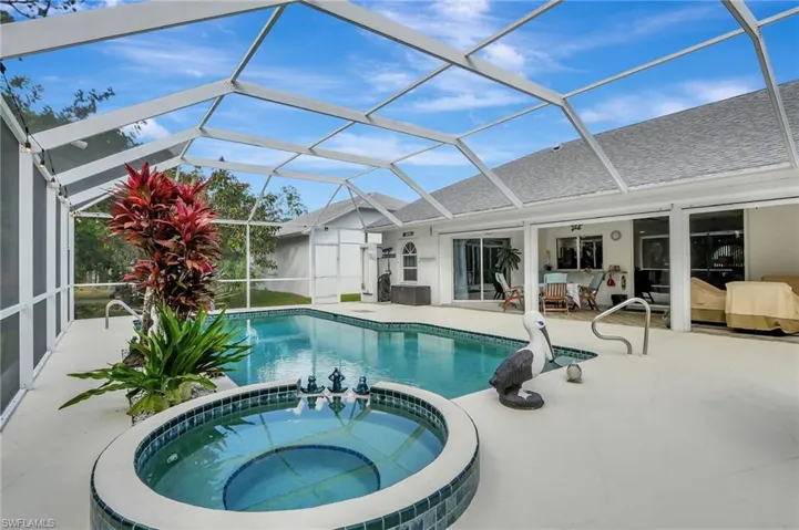 Screened lanai featuring a swimming pool, integrated spa with tile surround, and expansive concrete decking