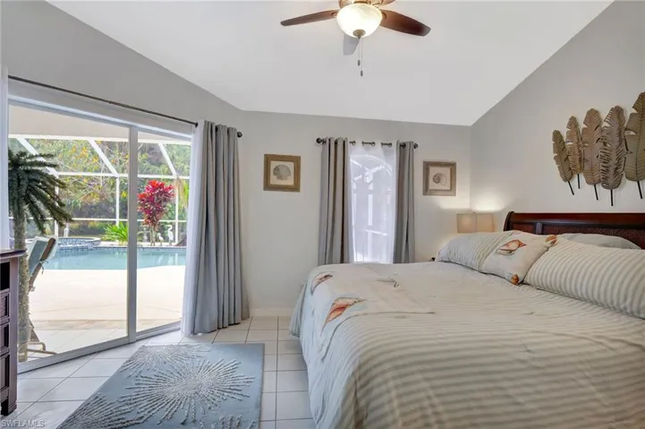 Interior room featuring ceramic tile flooring, a vaulted ceiling, a ceiling fan with integrated lighting, and direct access to an outdoor screened enclosure via sliding glass doors