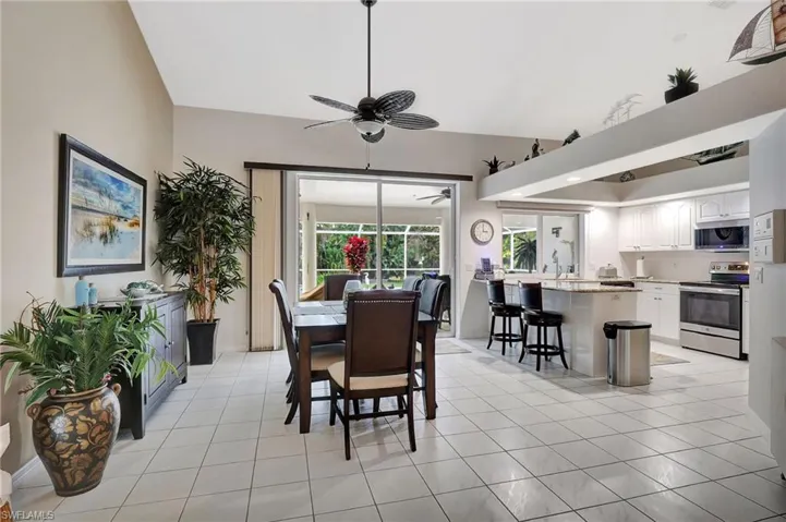 Open-concept dining area featuring tiled flooring, a ceiling fan, and sliding glass doors opening to a screened patio