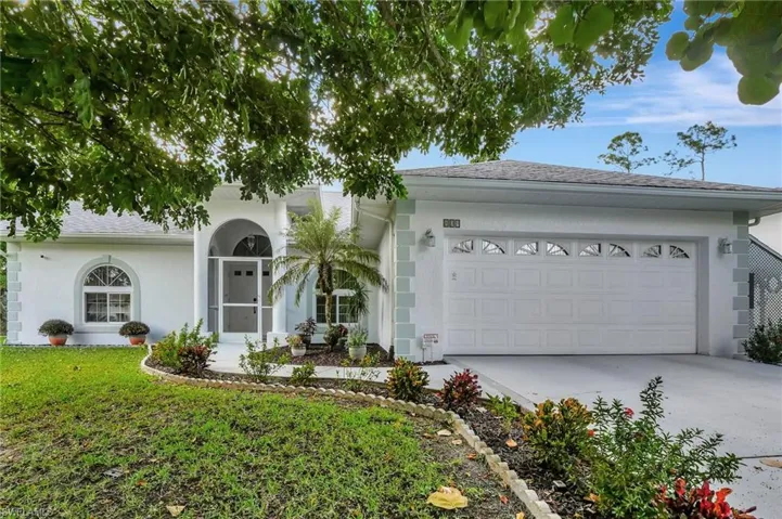 White stucco exterior with arched entry, screened front door, arched windows, and a two-car garage with arched window inserts