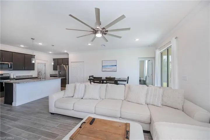 Living room featuring crown molding, wood tiled floors, a ceiling fan, and recessed lighting