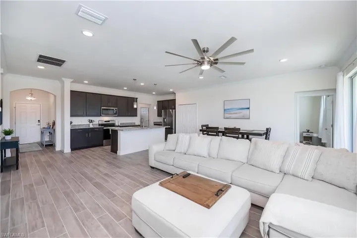 Living area featuring ornamental molding, wood finish floors, arched walkways, a ceiling fan, and recessed lighting
