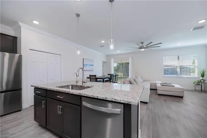 Kitchen with appliances with stainless steel finishes, wood tiled floors, light stone countertops, pendant lighting, and recessed lighting