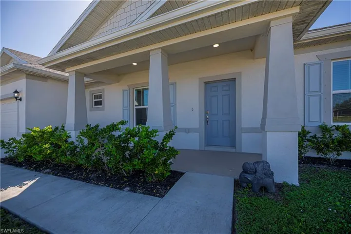 View of exterior entry with covered porch, stucco siding, and a garage
