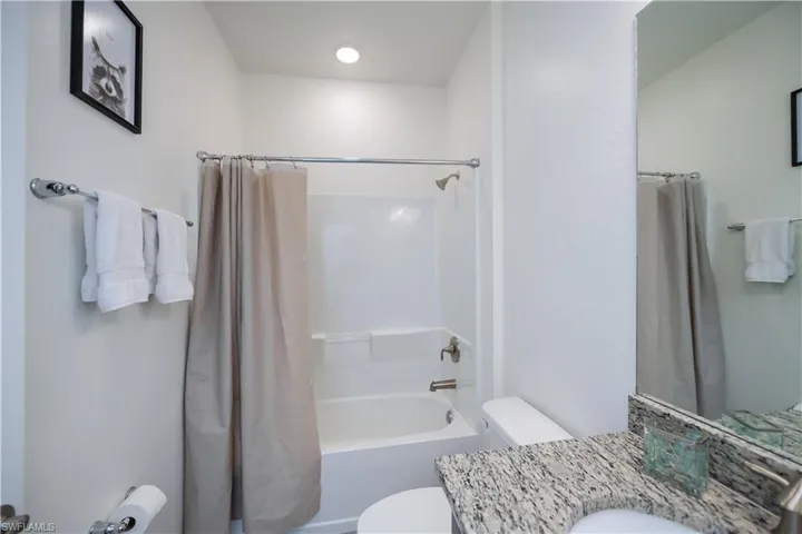 Bathroom featuring shower / bathtub combination with curtain and vanity