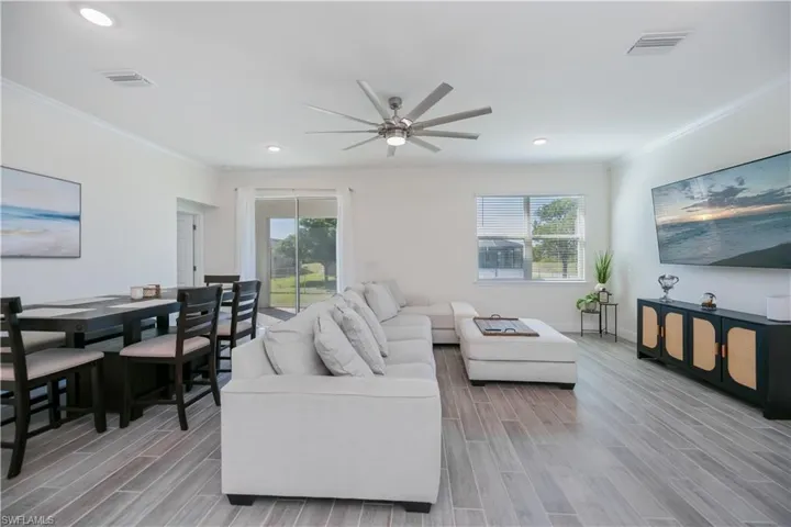 Living room featuring molding, wood tiled floors, plenty of natural light, ceiling fan, and recessed lighting