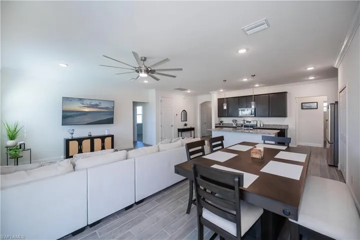 Dining space with wood tiled floors, arched walkways, ceiling fan, recessed lighting, and crown molding