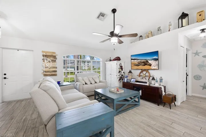 Living room featuring ceiling fan and light wood plank ceramic tile-style flooring