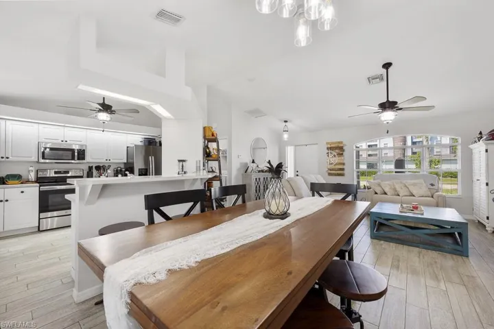 Dining room featuring a ceiling fan, light wood-type ceramic tile flooring, and vaulted ceiling